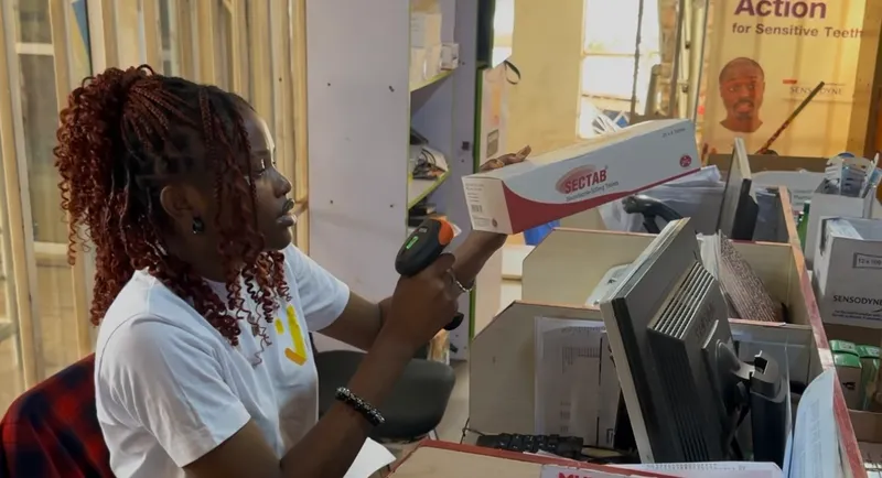 A Saletick agent scanning a medicine box with a barcode scanner at a pharmacy counter