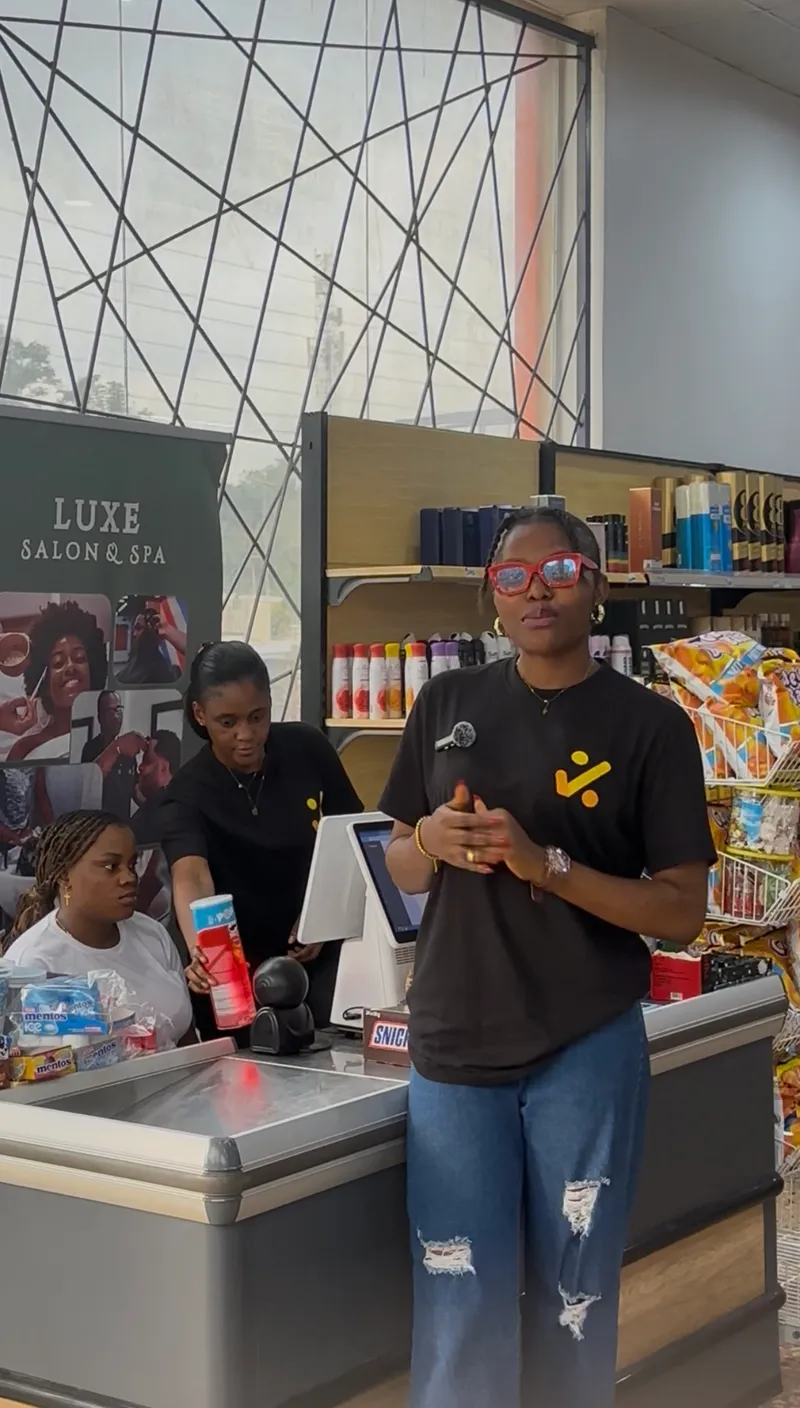 A Saletick trainer in a Saletick t-shirt talking a supermarket's cashiers through the checkout system